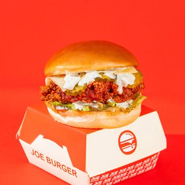 Spicy fried chicken sandwich with pickles and creamy sauce on a soft bun.