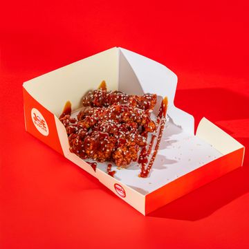Fried chicken drizzled with sauce and sesame seeds in a Joe Burger box.