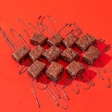 Chocolate brownies drizzled with chocolate sauce on a red background.
