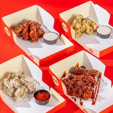 Variety of sauced chicken wings with dipping sauces in branded boxes.