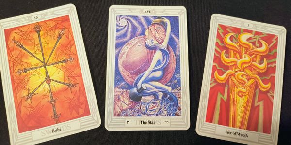 Three tarot cards featuring swords, a star figure, and wands on a black background.