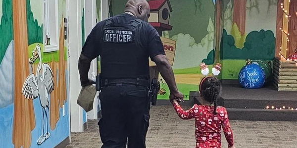 Security officer holding toddler walking