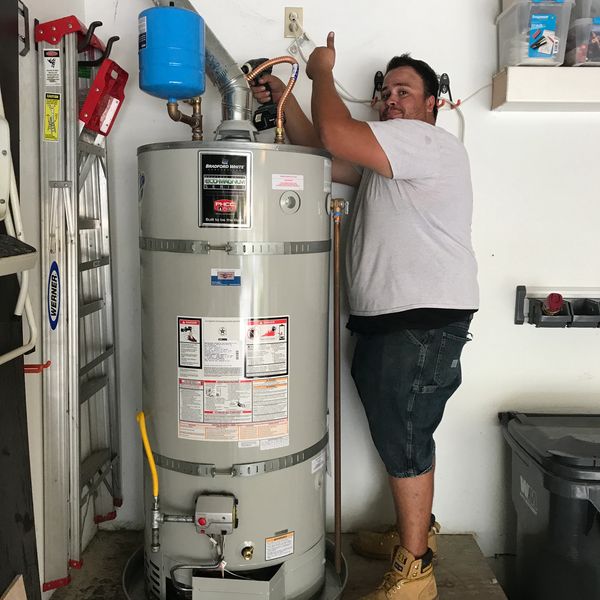 Man installing a water heater in a garage.