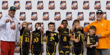 Youth basketball team proudly displays medals and trophy with coaches.