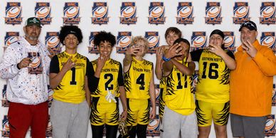 Youth football team posing with coaches at a sports event.