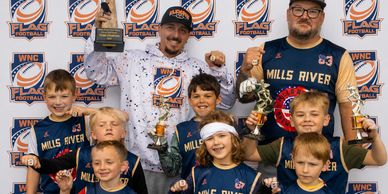 Youth flag football team celebrating with trophies and medals.