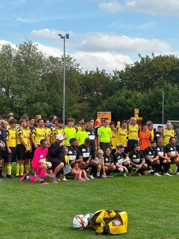 Two soccer teams pose together on a field before a match.