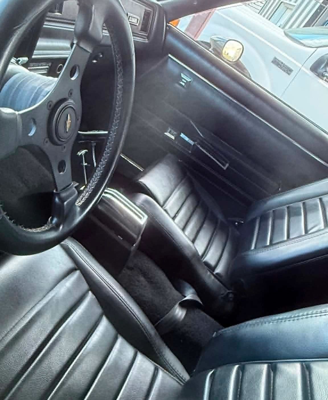 Interior view of a classic Chevrolet car with black leather seats and steering wheel.