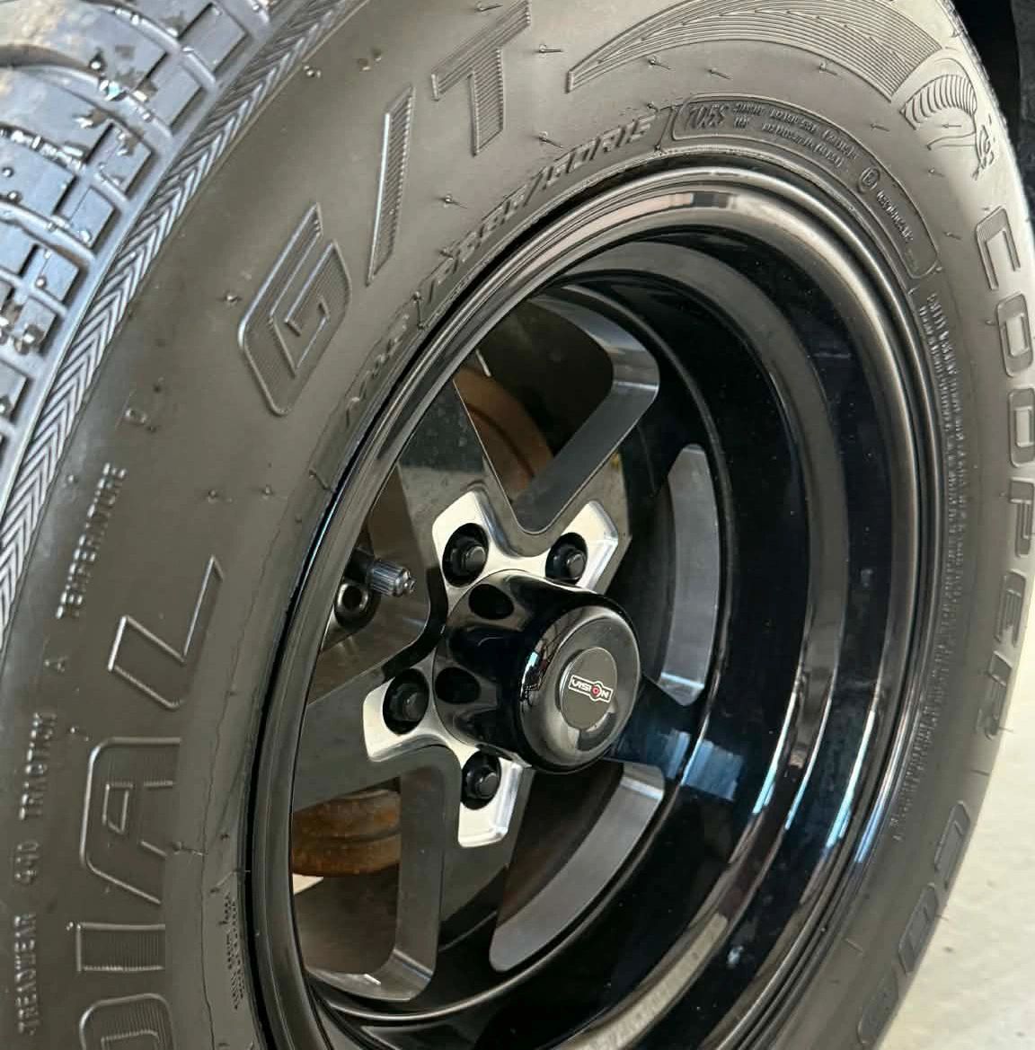 Close-up of a black Vision wheel rim on a Cooper tire.