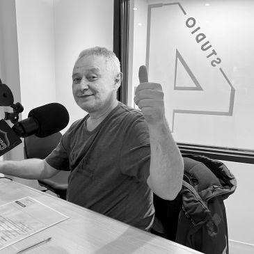 Homme souriant donnant un pouce levé dans un studio radio.