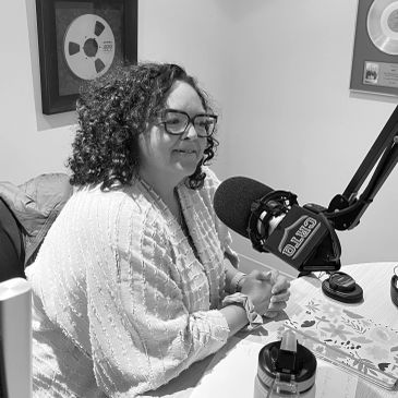 Une femme souriante parle dans un micro de studio.