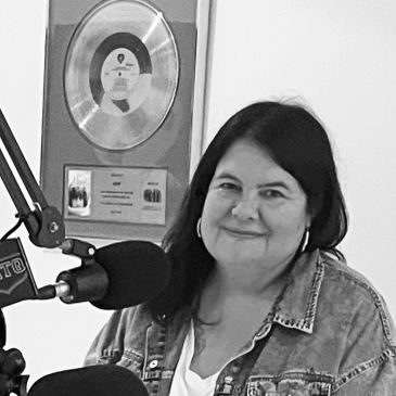Femme souriante devant un microphone en studio de radio.