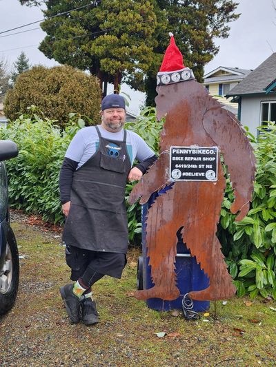 Shane penny at work leaning against brown Big Foot Sign