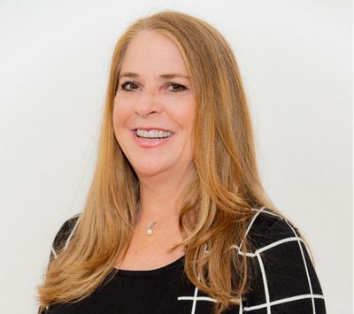Smiling woman with long blonde hair and a patterned black top.