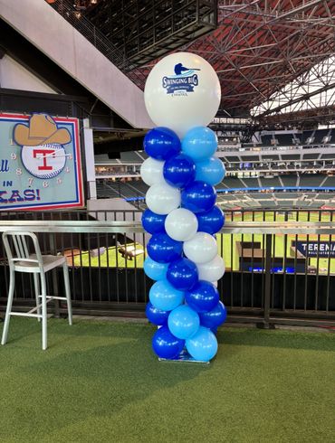 Tall balloon column with blue and white balloons at a baseball stadium.