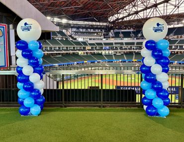 Two blue and white balloon columns at a baseball stadium.