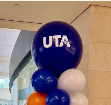 Cluster of blue, white, and orange balloons with UTA logo on the largest balloon.