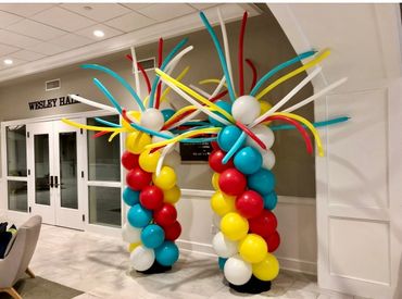 Colorful balloon columns with long balloons on top inside a building entrance.