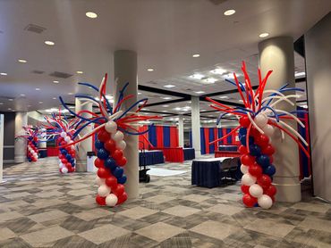 Red, white, and blue balloon columns decorate a spacious event hall.