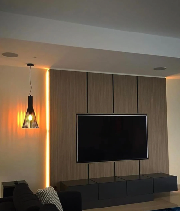 Modern living room with wall-mounted TV and warm lighting.