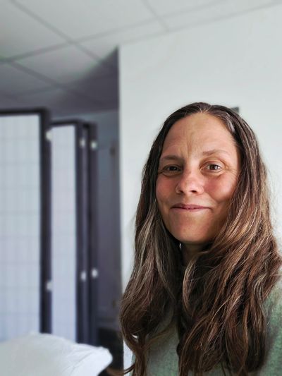 Woman with long brown hair smiling gently.