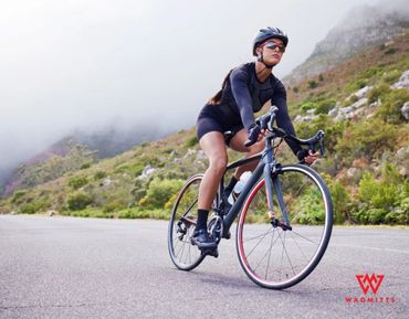 Female Cyclist on a mountain side road with Wadmitts Extra Thick Padded Cycling Glove Logo Top Left