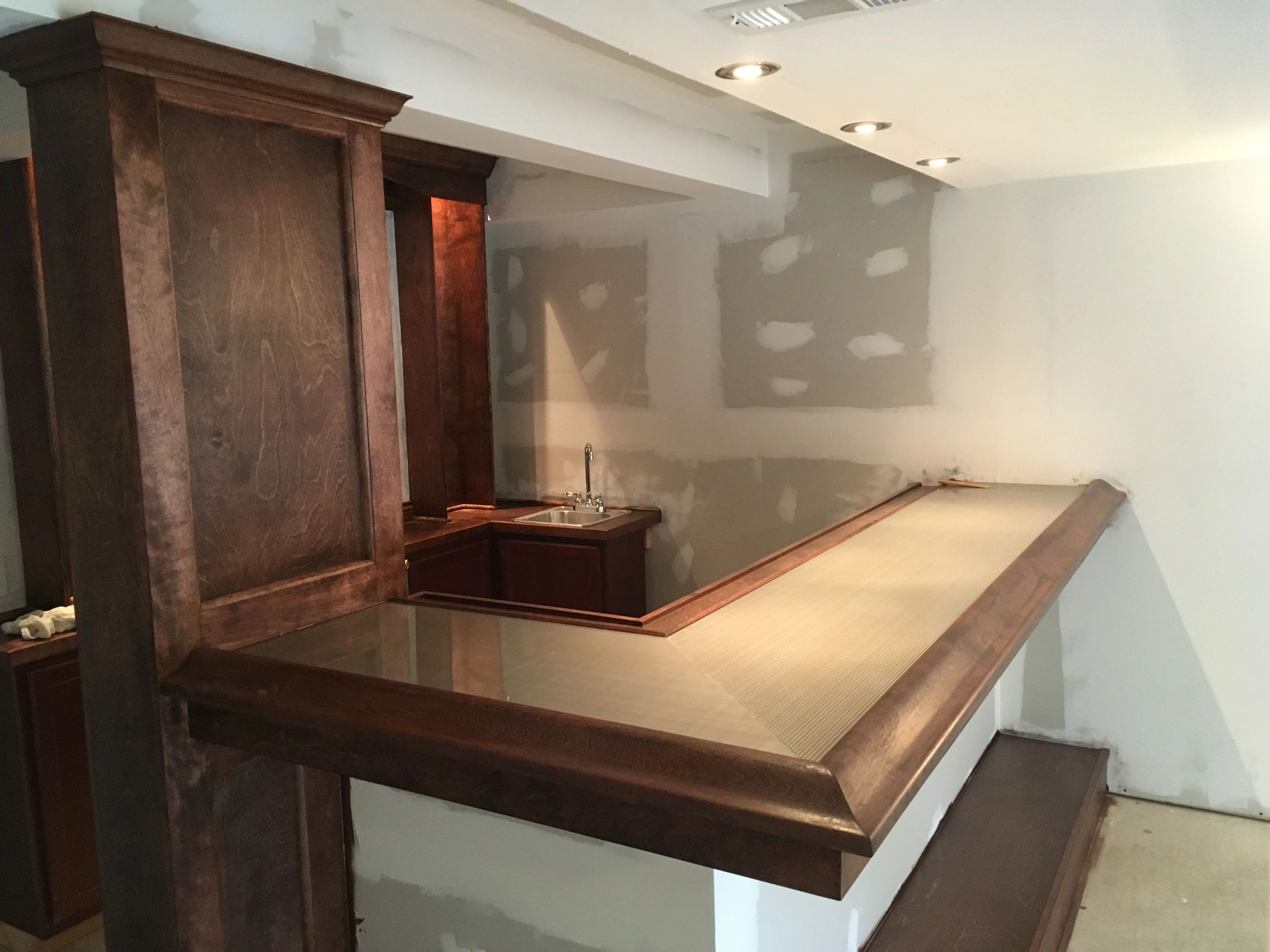 Wooden bar counter setup in a partially finished room.