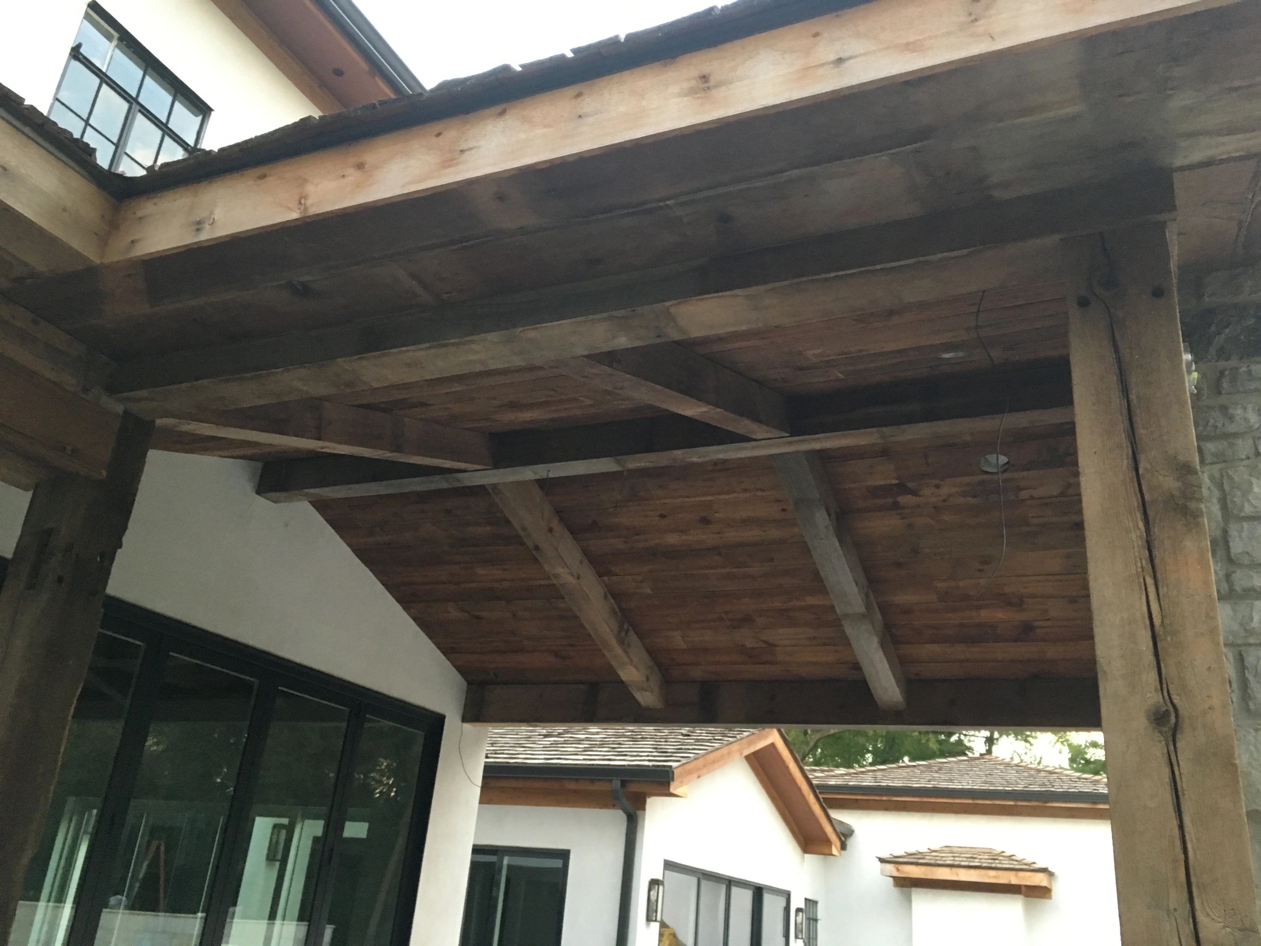 Rustic wooden ceiling beams in an outdoor patio area of a house.