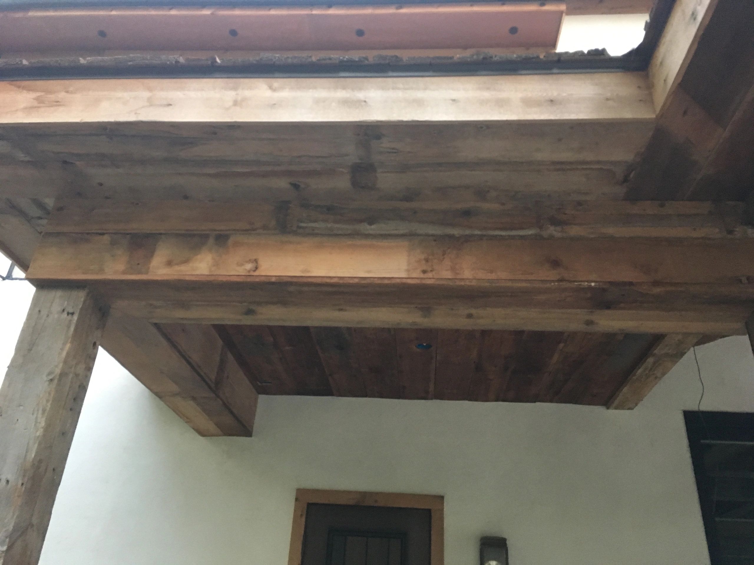 Rustic wooden ceiling beams over a doorway in a building.
