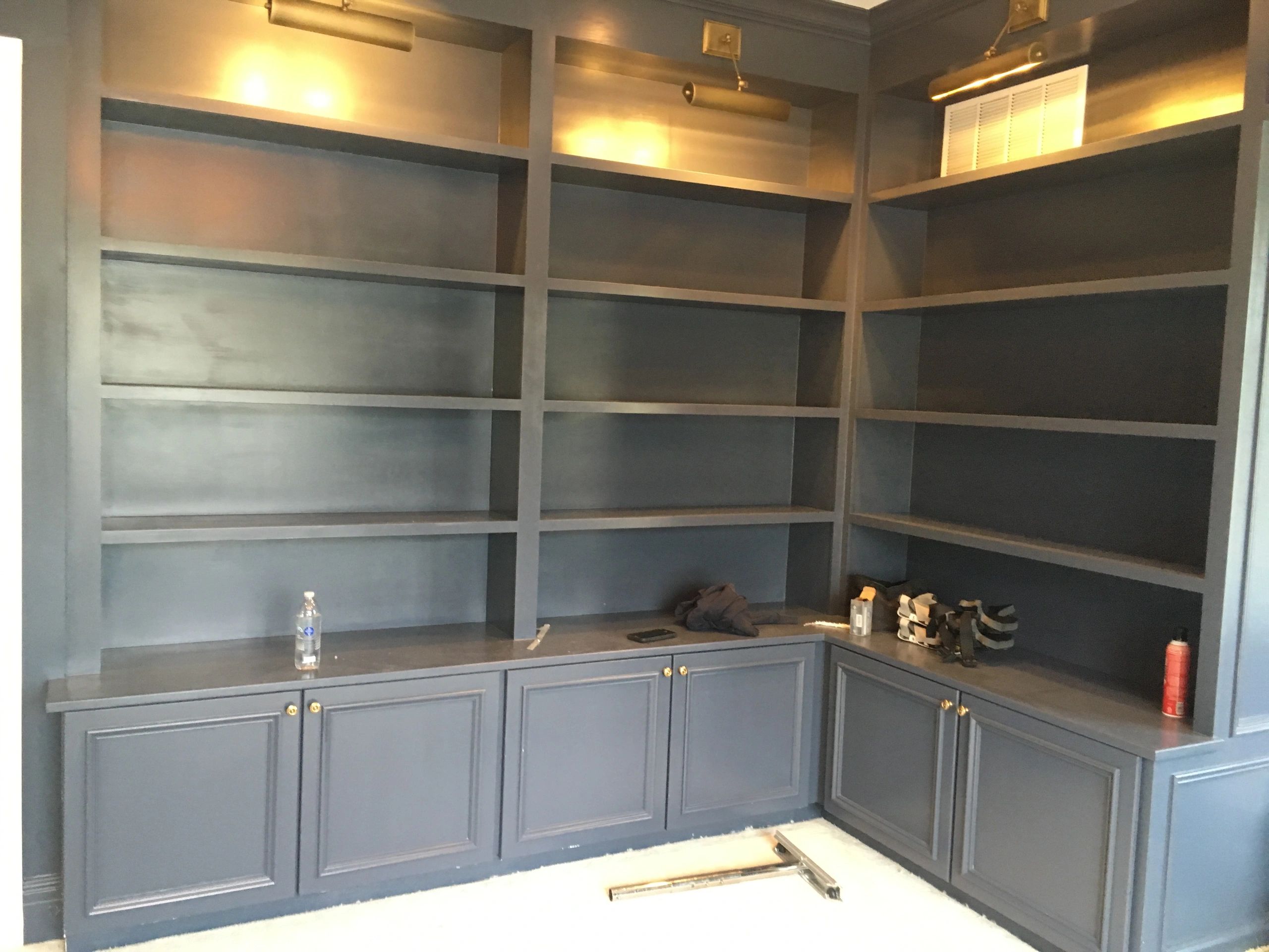 Empty blue built-in shelves with gold hardware and warm lights.