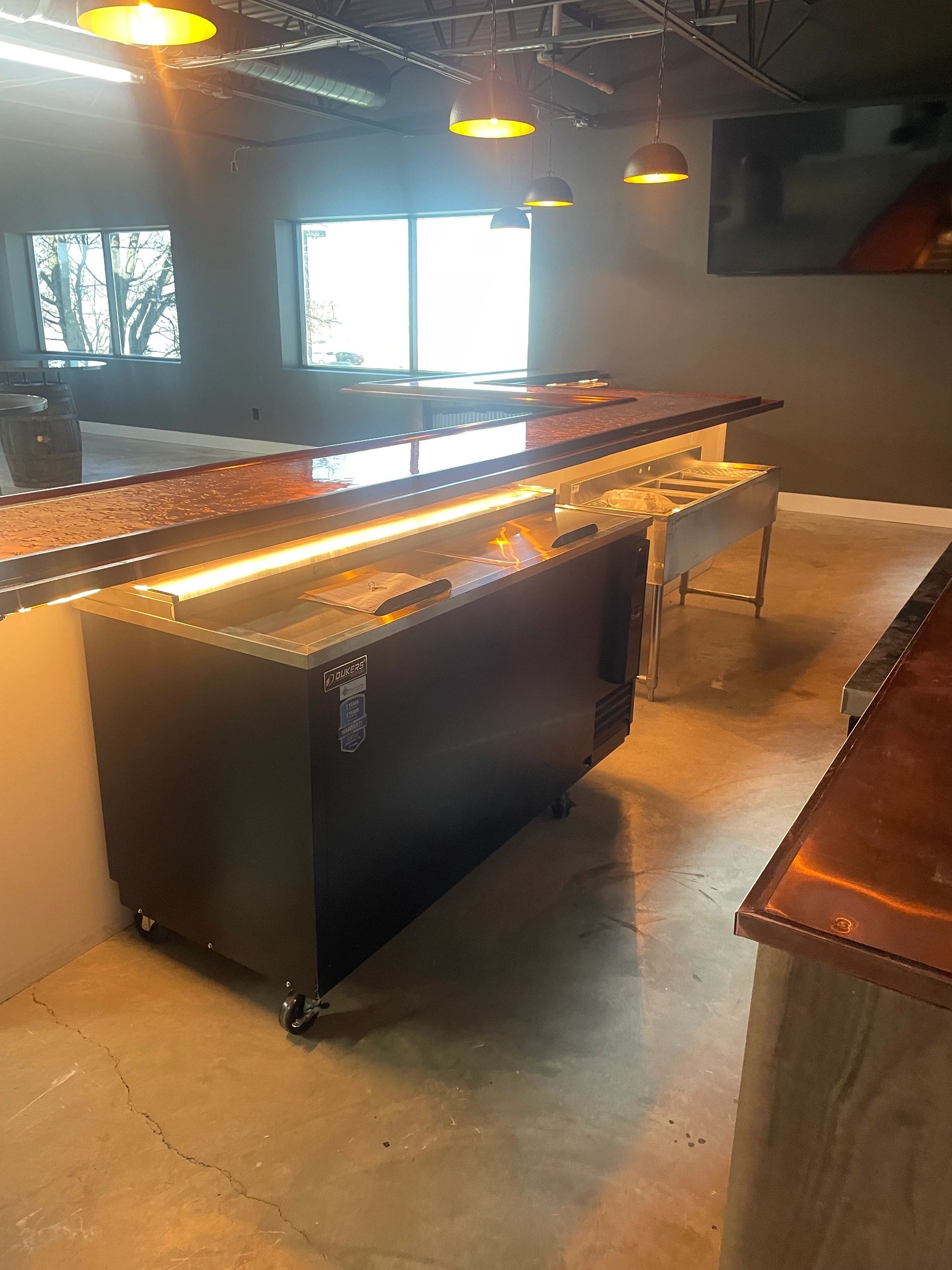 Modern bar area with copper countertops and industrial lighting.