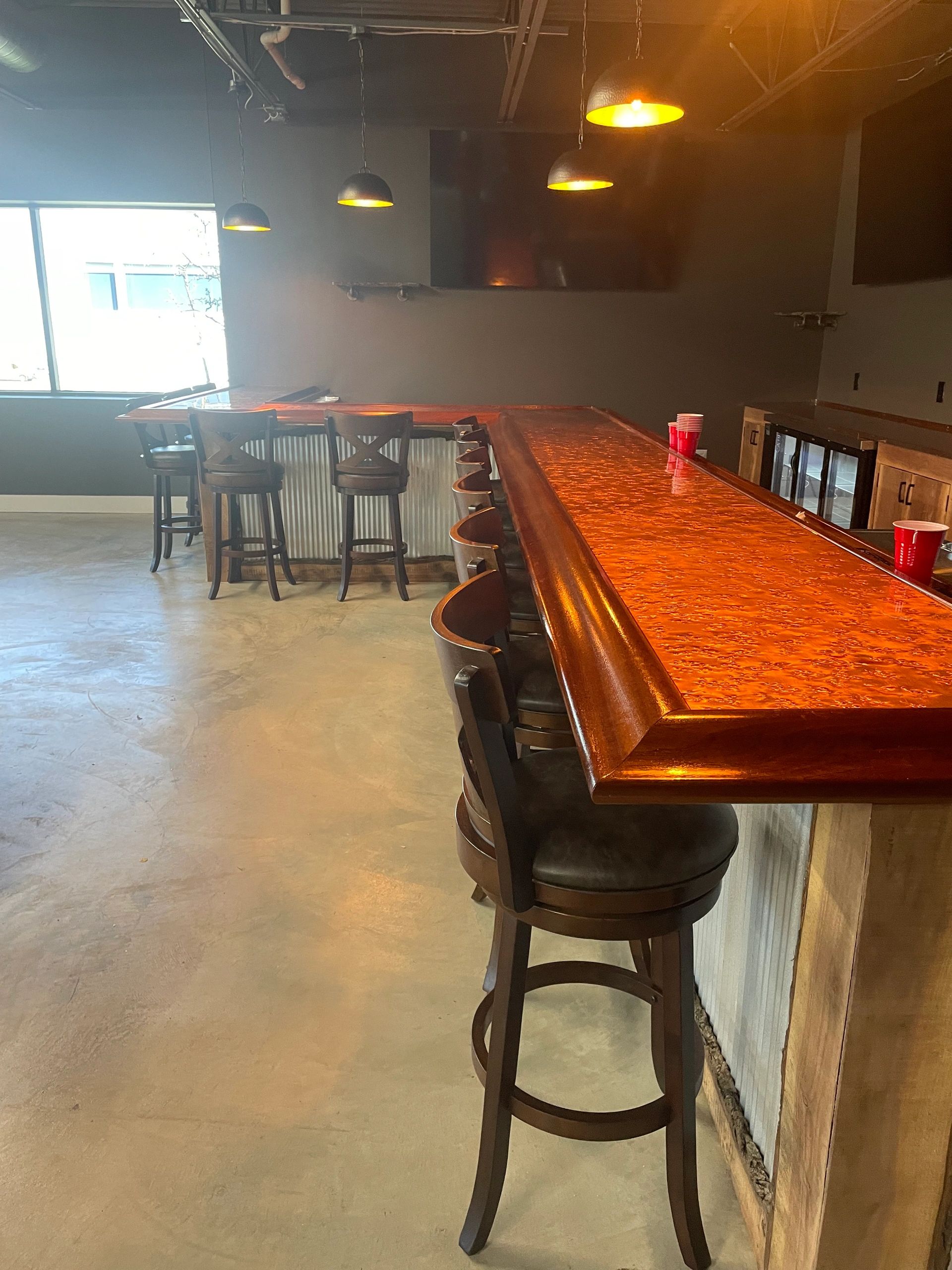 Empty bar with wooden stools and warm lighting.