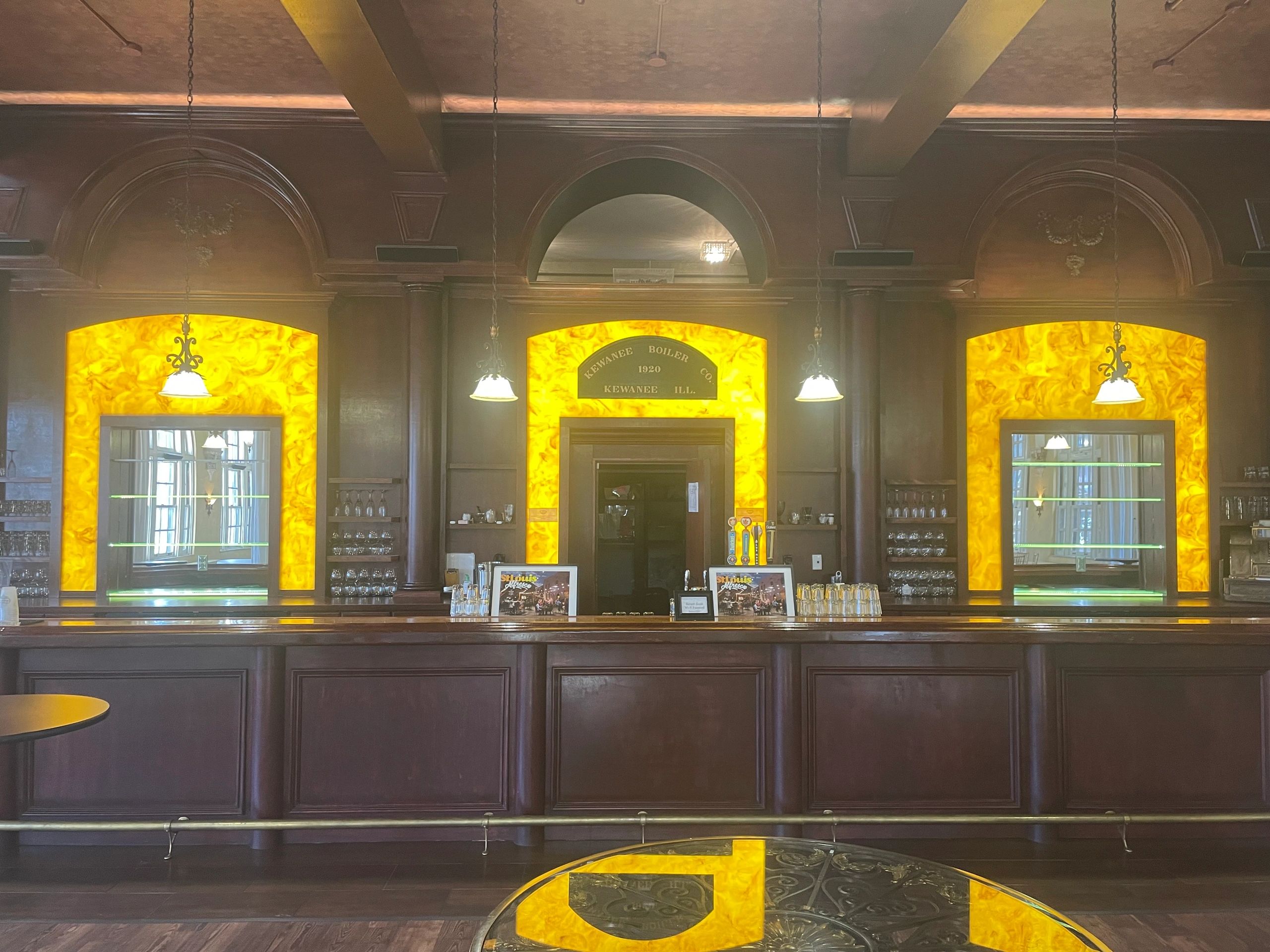 Elegant bar with glowing yellow backlit panels and hanging lights.