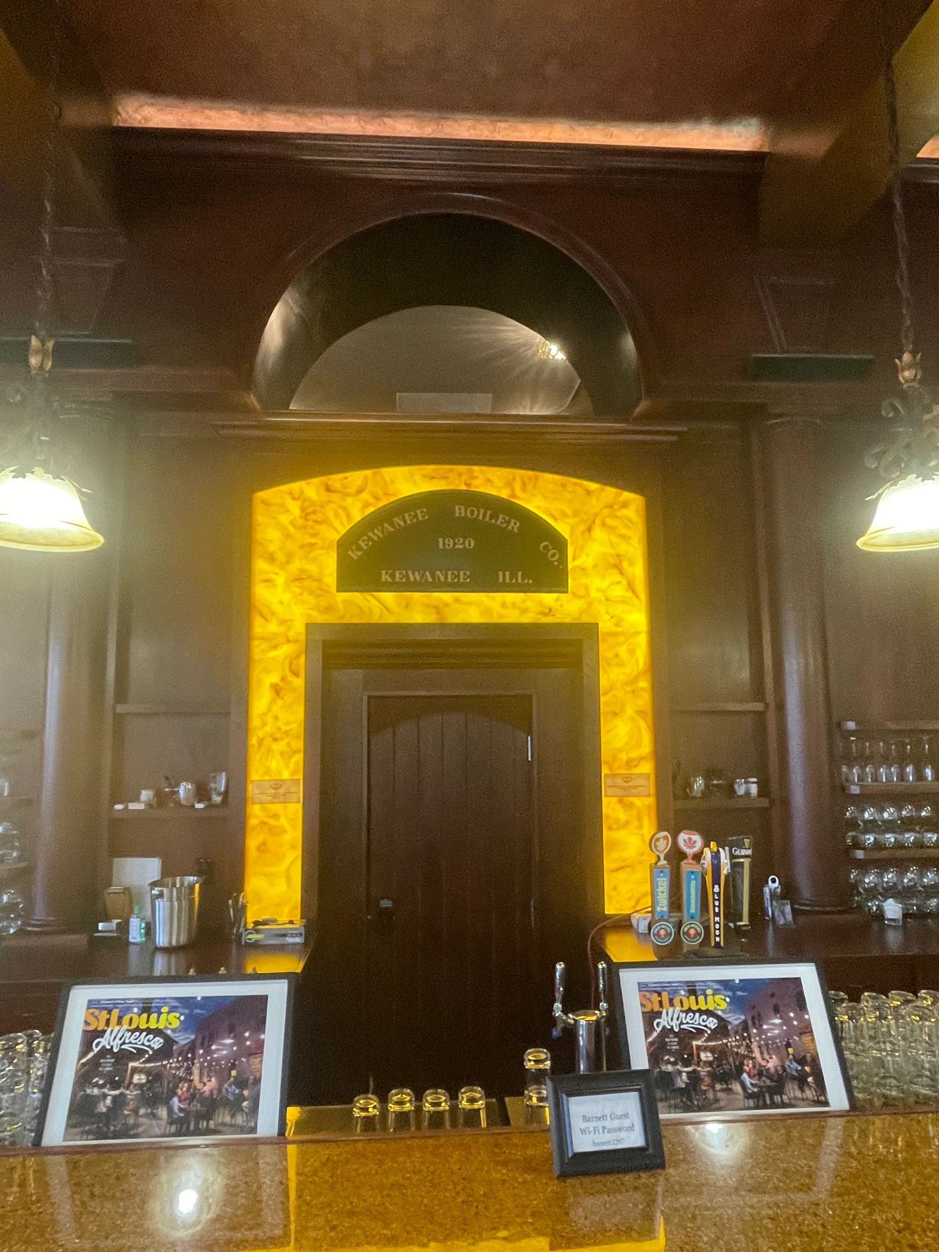 Bar interior with vintage boiler plaque and illuminated doorway.