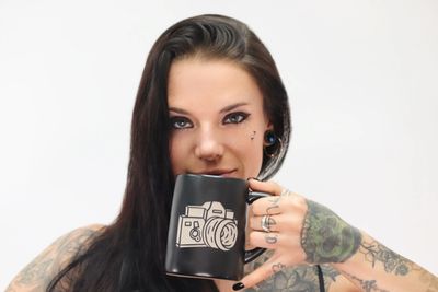 A tattooed woman holds a coffee cup.