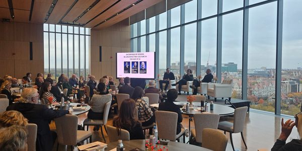 A panel discussion with an audience in a modern glass-walled room.