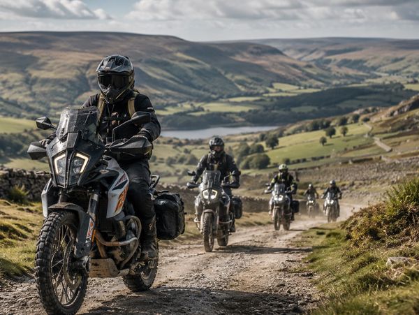 Group of motorcyclists riding on a dirt trail through scenic hills.