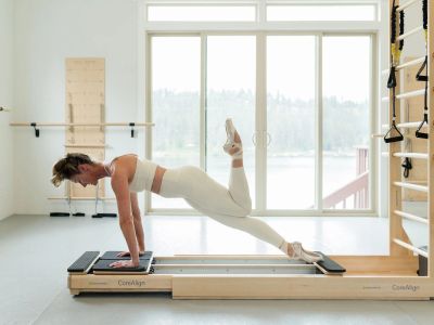 Woman exercising on a reformer machine in a bright studio.
