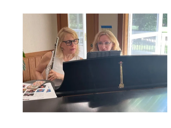 2 students reading music and sitting at the piano