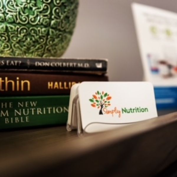 Business card holder with Simply Nutrition logo on a desk with nutrition books.