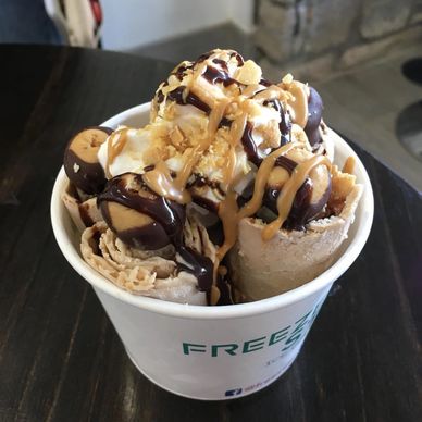Rolled ice cream topped with chocolate and peanut butter drizzle.