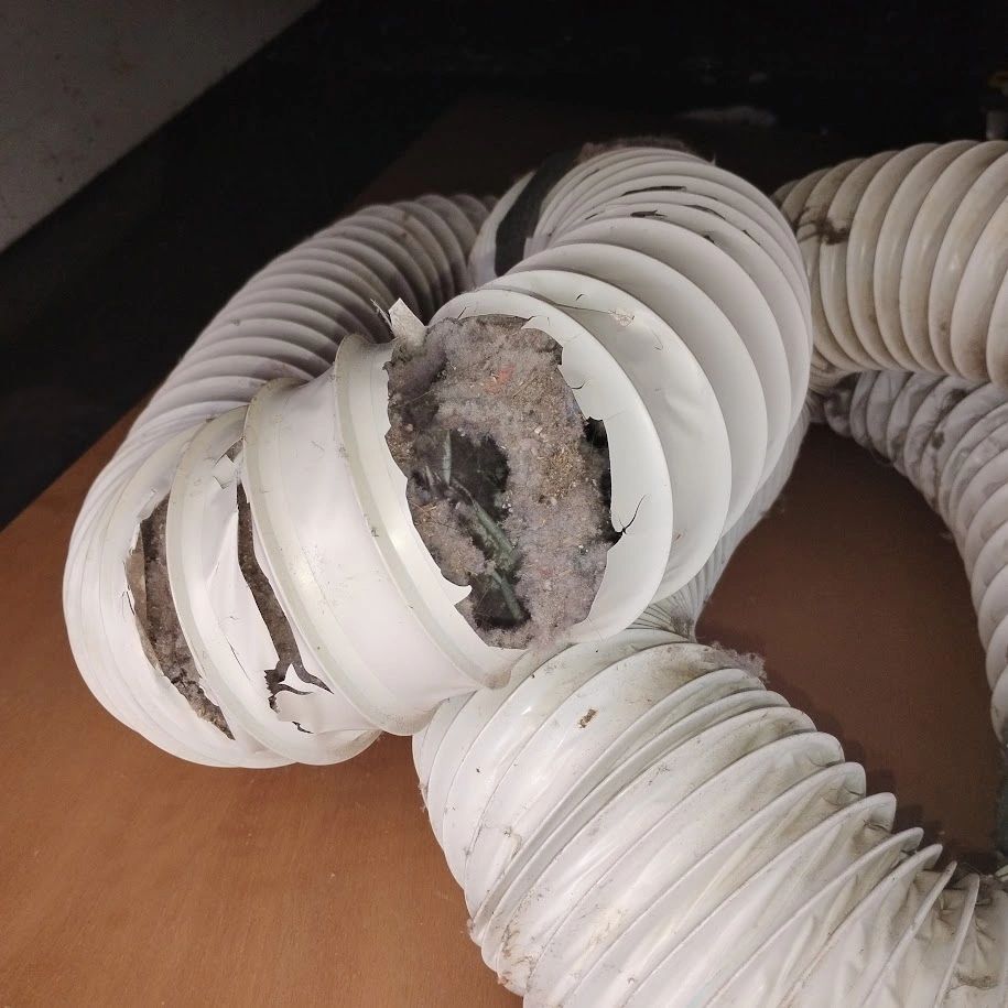 Damaged white flexible ducts filled with dust and debris.