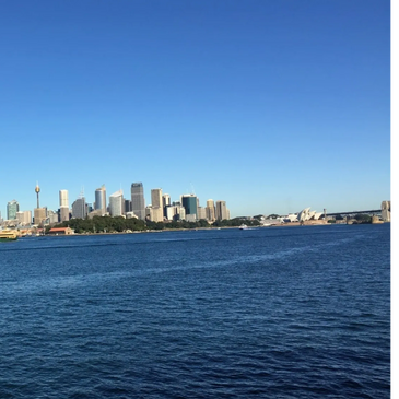 Sydney skyline with the Opera House under a clear blue sky.