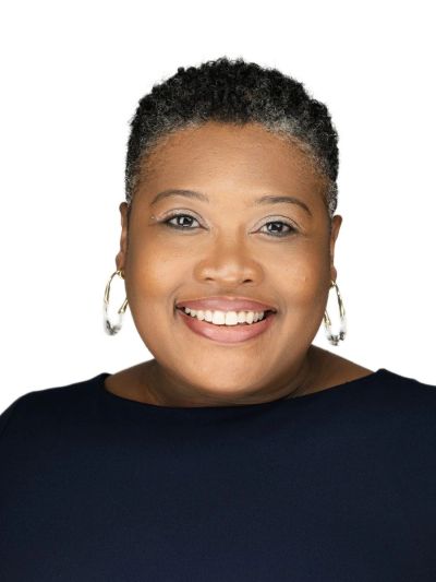 Smiling woman with short curly hair and hoop earrings.