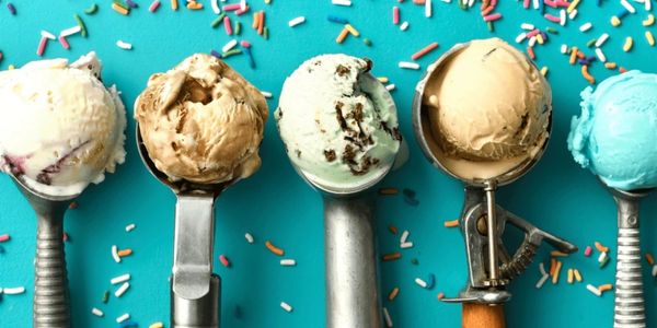 Five scoops of colorful ice cream on scoops with sprinkles on a blue background.
