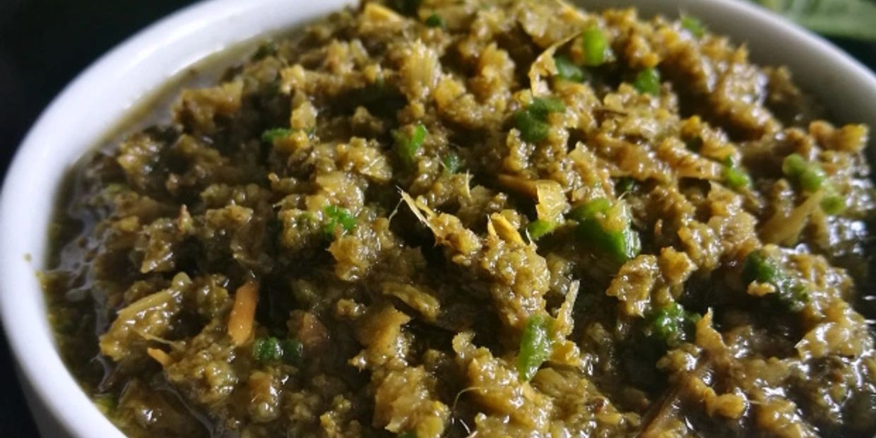 Close-up of a green chutney or relish in a white bowl.
