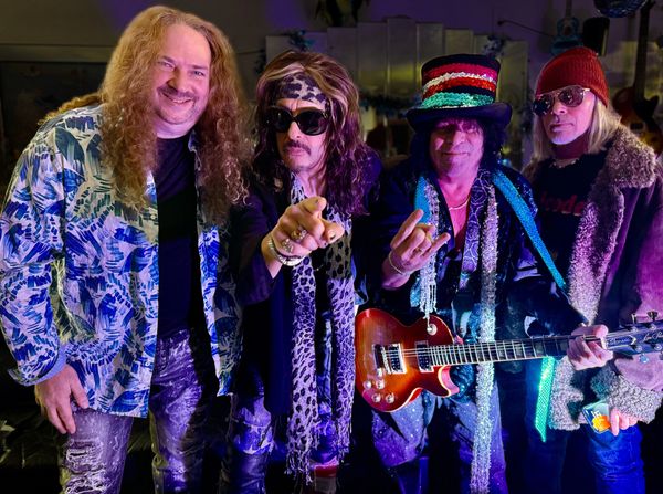 Four rock musicians posing with guitars and vibrant outfits.