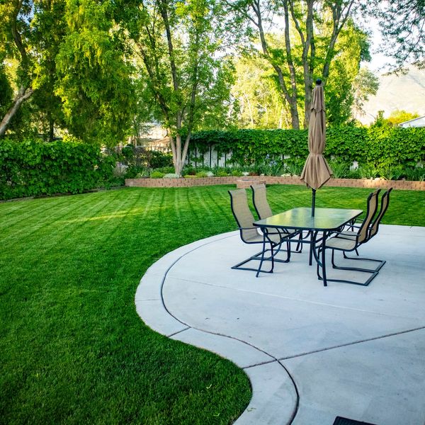 A garden with trimmed lawn and a table on the patio
