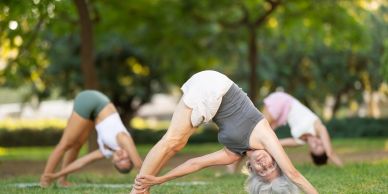 Three people practicing yoga outdoors.