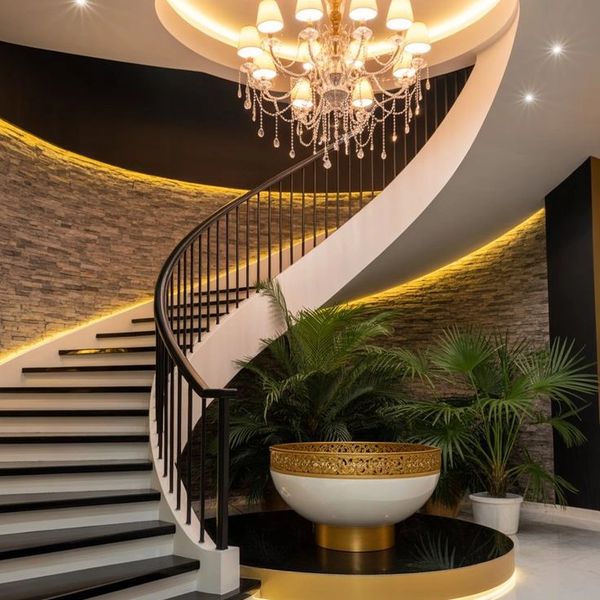 Elegant spiral staircase with chandelier and lush plants in a modern interior.